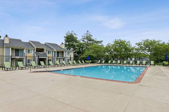 A swimming pool surrounded by lounge chairs and trees at Chinoe Creek Apartments, Lexington 40502
