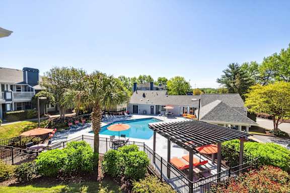 an aerial view of a pool with umbrellas and a building in the background at Palmetto Place Apartments, Taylors, SC, 29687