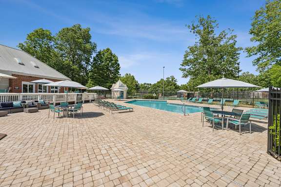 A large outdoor patio with a pool and umbrellas. at The Timbers Apartments, Richmond, VA, 23235