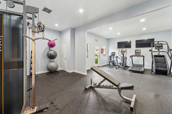 A gym with a variety of equipment including a squat rack, bench, and weights.