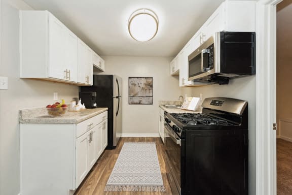 a kitchen with black appliances and white cabinets at Hyde Park Townhomes, PRG Real Estate Management, Chester, VA