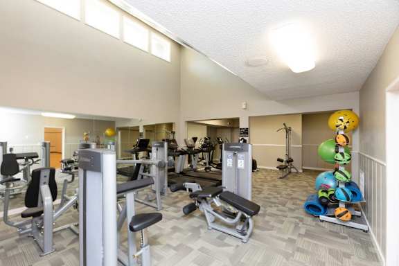 A gym with a variety of equipment including weights and machines at Lakecrest Apartments, PRG Real Estate Management, Greenville, SC 29615