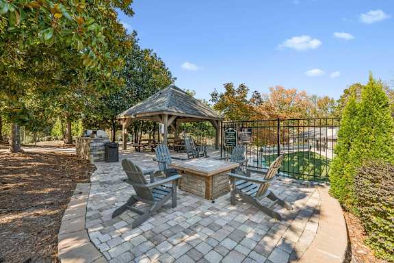 A gazebo is surrounded by chairs and a table in a backyard. at Park Ridge Estates, Durham, 27713
