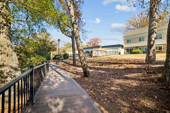 A wooden walkway with a metal railing is surrounded by trees at Lakecrest Apartments, PRG Real Estate Management, Greenville, SC 29615