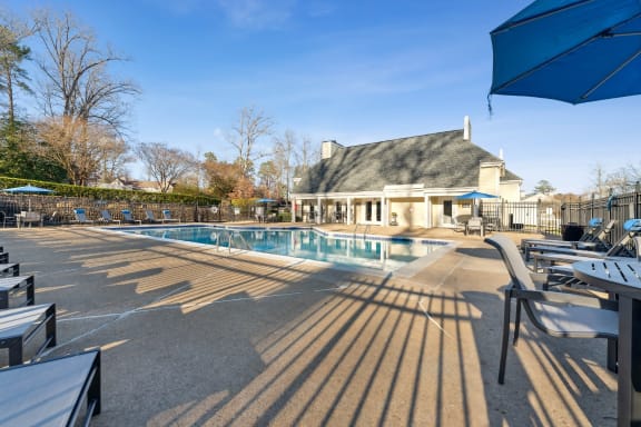 a swimming pool with chairs and umbrellas in front of a house at Ashton Creek, Chester