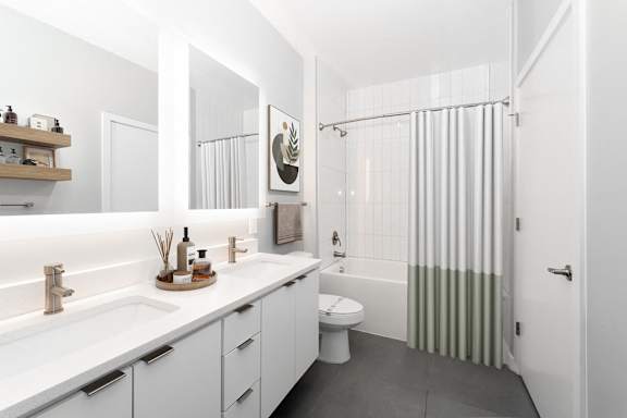 A white bathroom with a toilet, sink, and shower. at The Locks Tower, Richmond, 23219