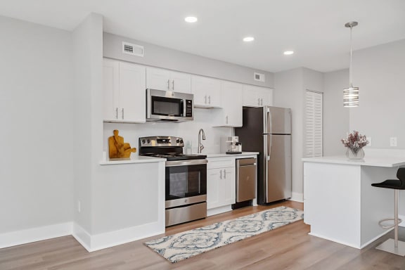 A kitchen with white cabinets and a black chair  at The Courtyards of Chanticleer Apartments, Virginia Beach, VA, 23451