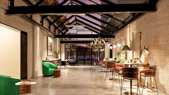 A modern interior with a glass ceiling and a mix of green and brown furniture at The Carousel, Richmond, VA