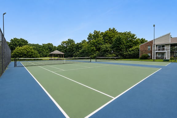 A tennis court with a green and blue surface surrounded by a fence.