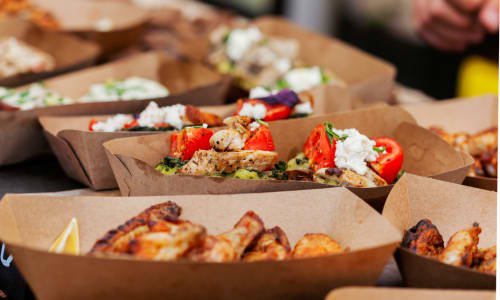 A variety of foods are served in paper trays.