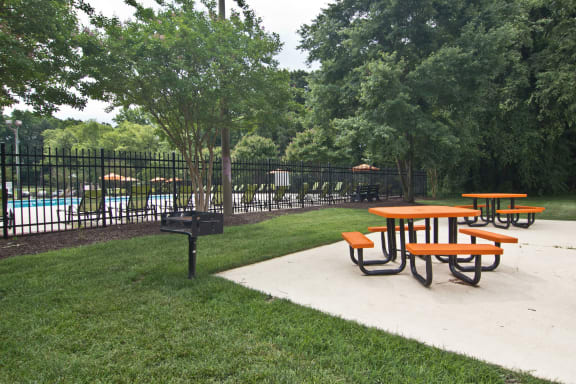 Picnic tables are set up in a park next to a pool. at Staples Mill Townhomes, Richmond, VA 23228