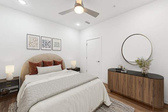 A bedroom with a large bed, a wooden cabinet, and a round mirror on the wall. at Hydro, Richmond, Virginia