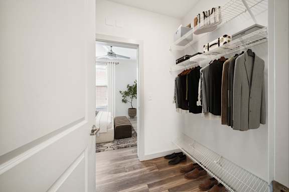 A hallway with a white door and a row of hanging coats at Circ Apartments, Virginia