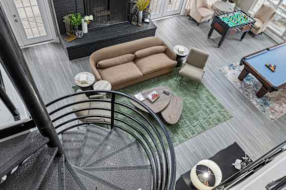 A living room with a pool table and a spiral staircase.