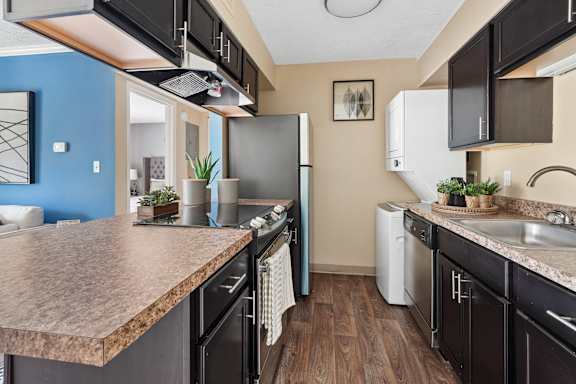 A kitchen with black appliances and a brown countertop.