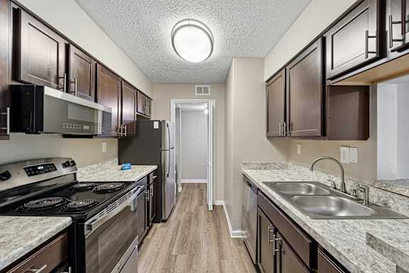 A kitchen with dark brown cabinets and a white sink.