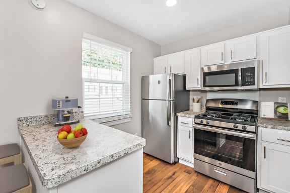 A kitchen with a granite countertop and stainless steel appliances. at Staples Mill Townhomes, Richmond, VA 23228