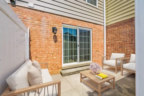 A patio with a table, chairs, and a window with bars. at Staples Mill Townhomes, Richmond, VA 23228