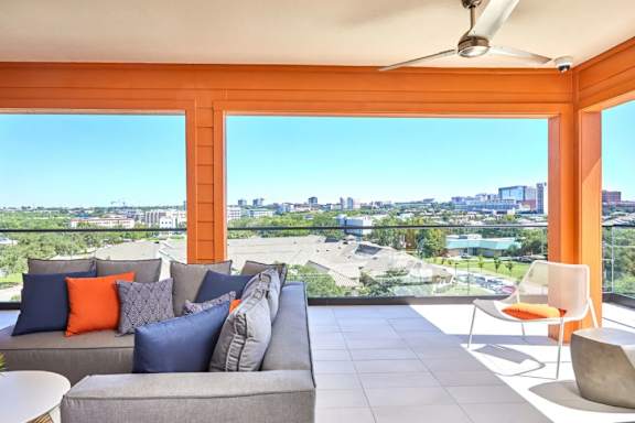 A living room with a grey couch and orange pillows at Addison Medical Center Apartments, San Antonio