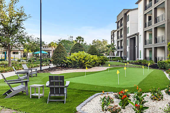 A miniature golf course is surrounded by chairs and flowers.