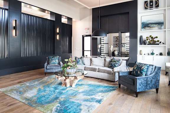 A living room with a blue rug and a grey couch.