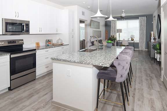 A kitchen with a granite countertop and bar stools.