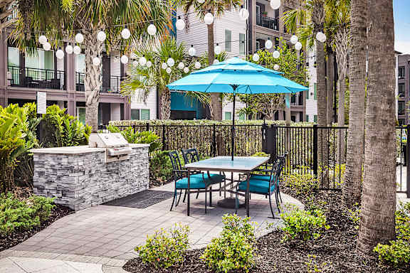 A patio with a table and chairs under a blue umbrella.