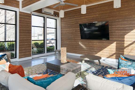 A living room with a white couch and a flat screen TV mounted on the wall.
