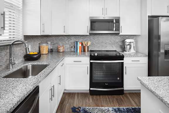 A modern kitchen with white cabinets and a black oven.
