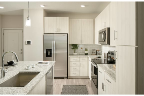 Model kitchen with island, hard floors, stainless steel appliances, and light cabinetry