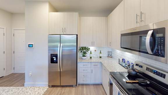 A modern kitchen with a stainless steel refrigerator and a black stove top oven.