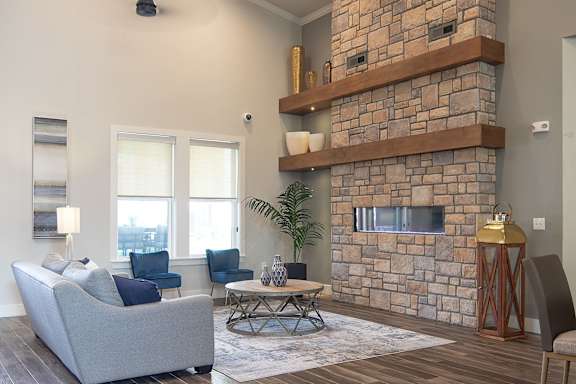A living room with a grey couch and a stone fireplace.