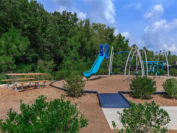Playground area with a slide, climbing equipment and swings at Berewick Pointe Apartments in Charlotte, NC