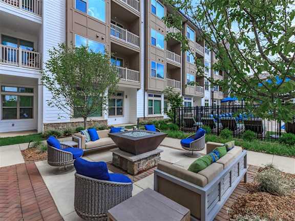 Large fire pit area near the pool with 2 couches at 4 4 chairs at Berewick Pointe Apartments in Charlotte, NC