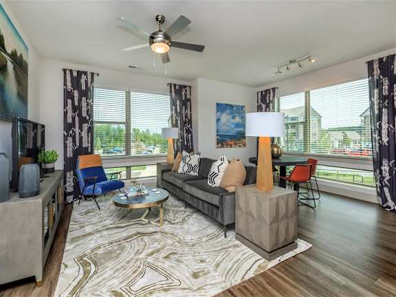 Oversized windows fill 2 walls in the furnished living room in an apartment Berewick Pointe in Charlotte, NC