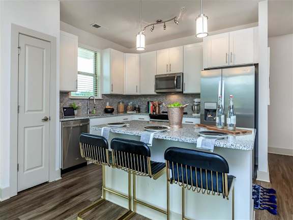 Stylish kitchen with tile backsplash, stainless steel appliances and an island at Berewick Pointe Apartments.