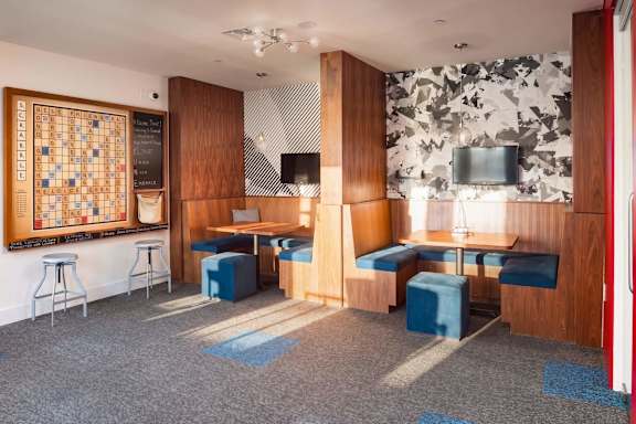 A room with a patterned wallpaper and a wooden panelled wall.