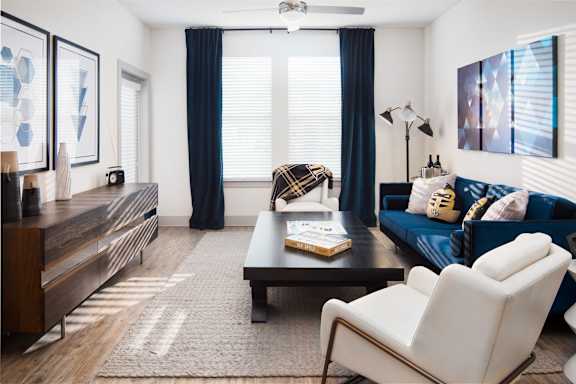 A living room with a blue couch and a white chair.