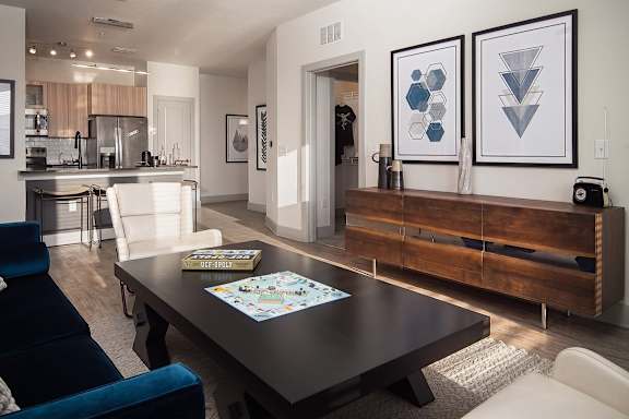 A modern living room with a dark wood coffee table and a blue velvet chair.