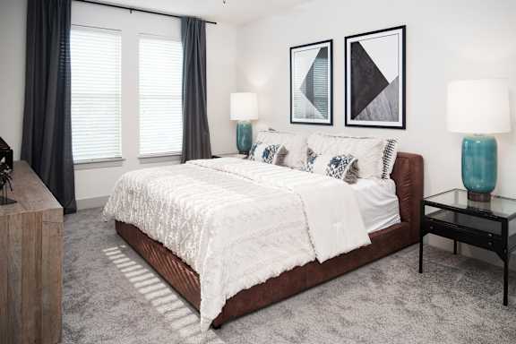 A bedroom with a large bed and two lamps.