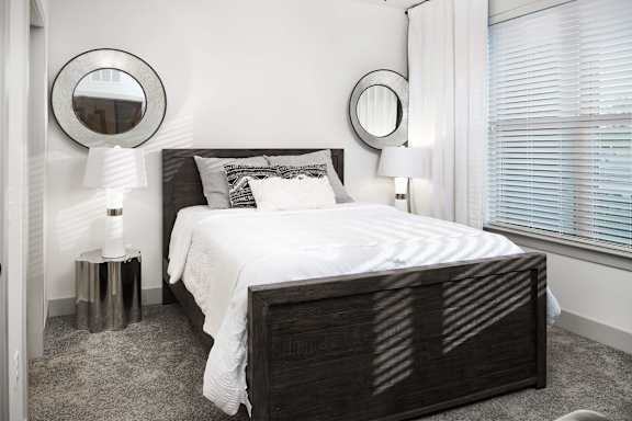 A bedroom with a large bed and two round mirrors on the wall.