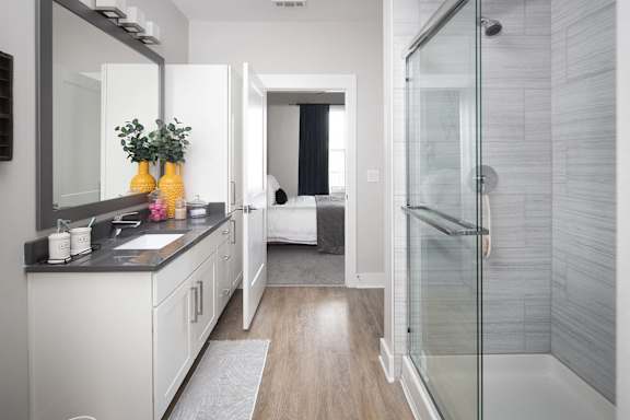 Ensuite bathroom with glass shower and white vanity at Pointe at Research Park Apartments, Charlotte, North Carolina