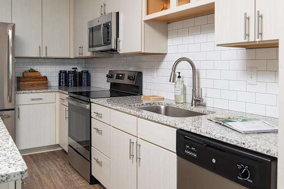 A kitchen with a black dishwasher and white cabinets.