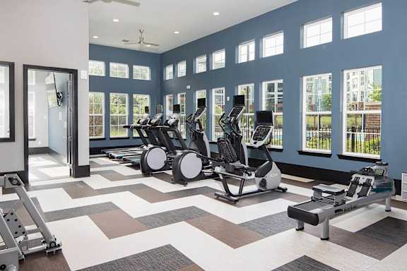 Fitness center with cardio machines and large windows at TRAILSIDE VERDAE Apartments, GREENVILLE, SC