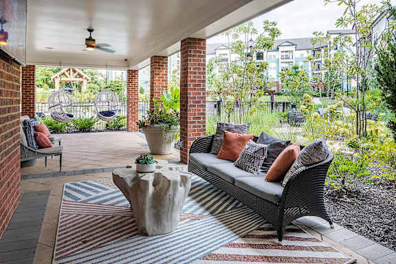 A patio with a couch, pillows, and a rug.