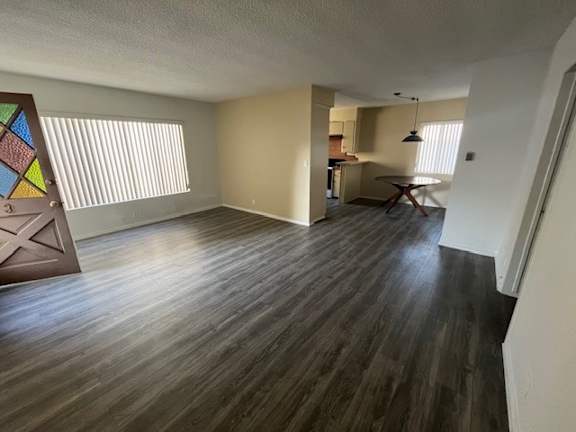 A room with wooden flooring and a large window with blinds.
