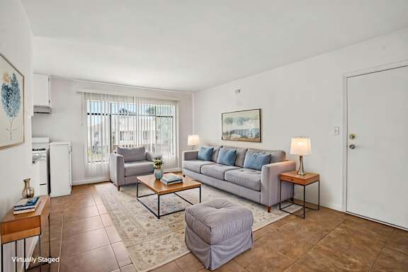 A living room with a grey couch, a coffee table, and a painting on the wall.