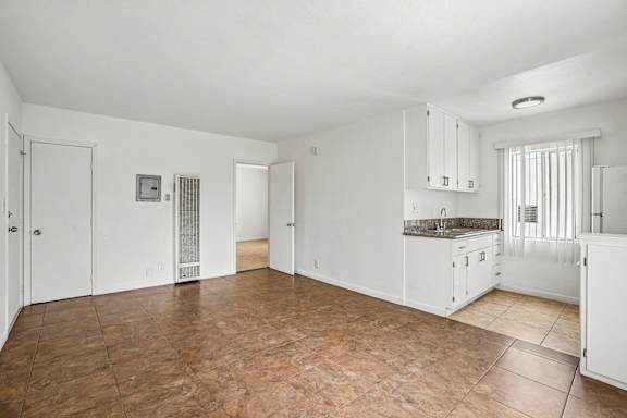 A kitchen area with white cabinets and a brown floor.
