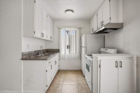 A kitchen with white cabinets and appliances.