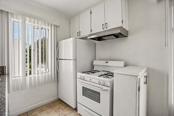 A white kitchen with a refrigerator, stove, and oven.